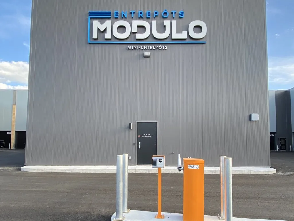 Le portail d’entrée des Entrepôts Modulo, devant le bâtiment et son enseigne